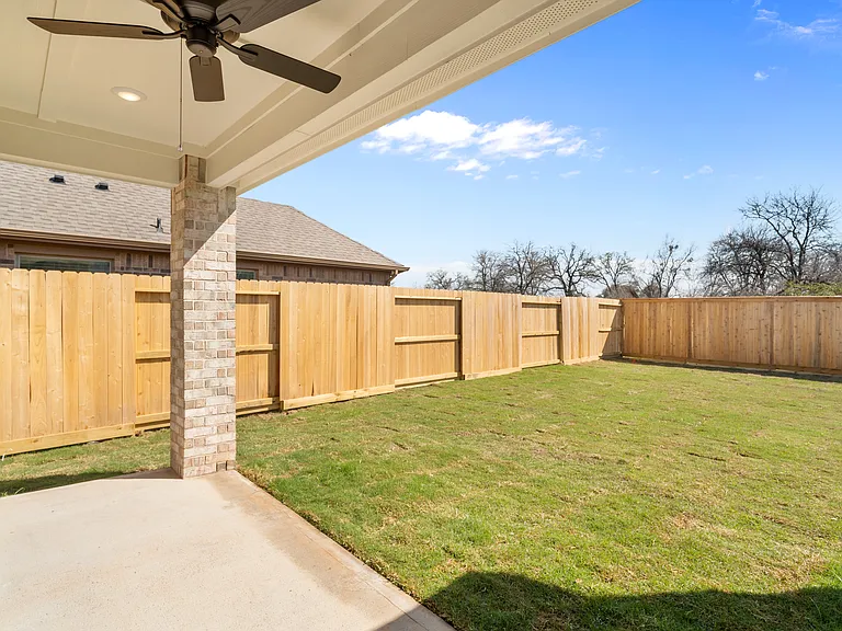 Covered back patio with ceiling fan, perfect for outdoor living year-round. Fully fenced backyard with wood privacy fence.