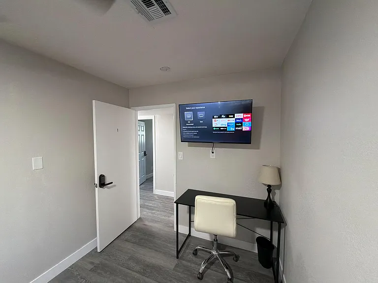 Private room with durable plank flooring, neutral walls, and a built-in desk area plus wall-mounted TV for work or relaxing.