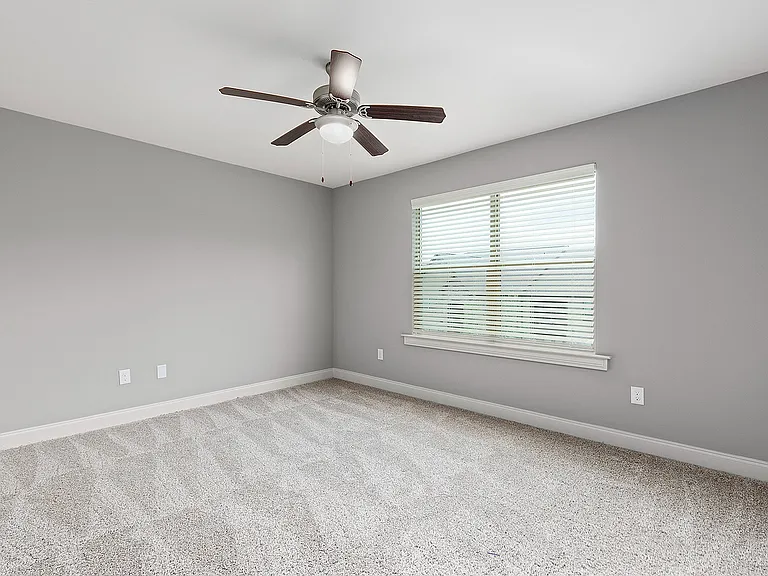 Bright and airy bedroom room with plush carpet, large window, and modern ceiling fan.