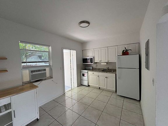 Bright open kitchen/living space with natural light and movable kitchen cart.