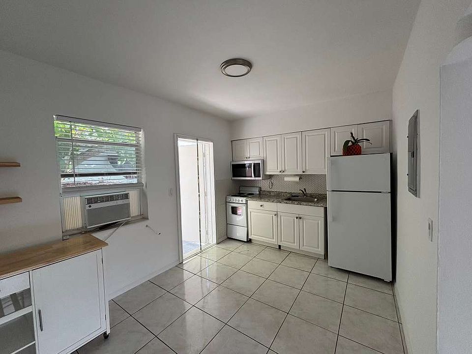 Bright open kitchen/living space with natural light and movable kitchen cart.