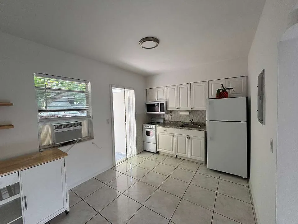 Bright open kitchen/living space with natural light and movable kitchen cart.