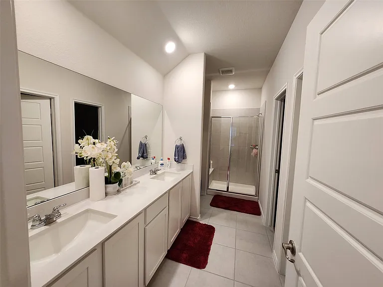 Double vanity with integrated sinks and chrome fixtures, extensive mirror, and recessed lighting