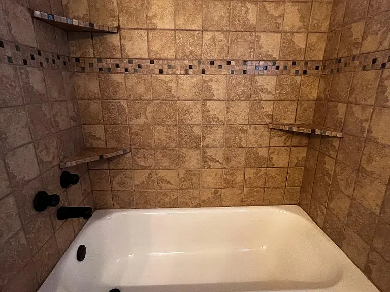 Hall Bath - Tub & Shower combo with full tile surround and shelves for bathing essentials.