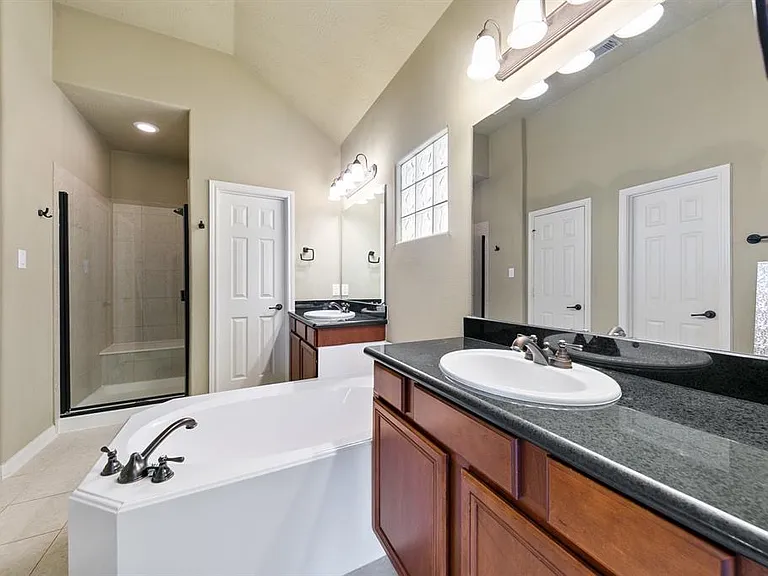 Spacious primary suite with double sinks, separate shower, soaking tub, and walk_in closet.