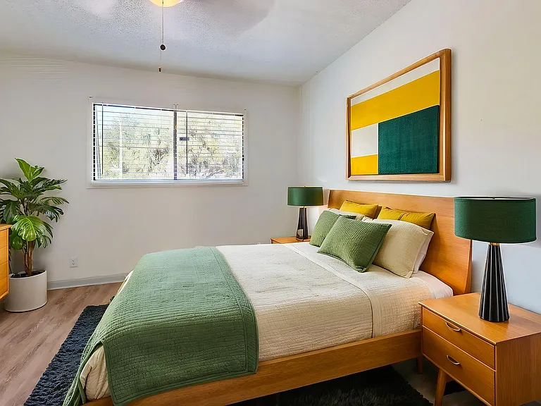 Modern bedroom with sleek wooden furniture, vibrant green accents, and contemporary artwork, creating a serene and inviting ambiance.