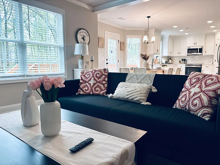 Open-concept living area with a comfortable seating zone flowing into a kitchen with island seating and ample cabinetry.