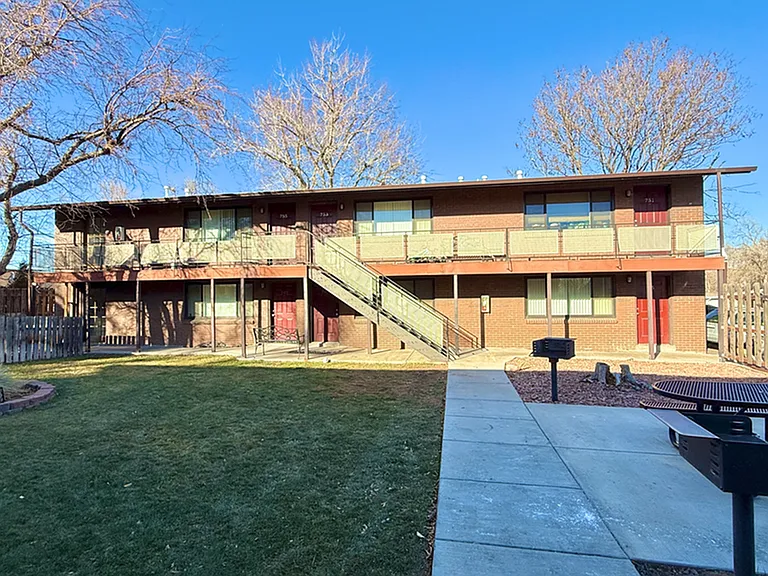 Charming brick apartment building with balconies and a scenic courtyard, perfect for outdoor relaxation.