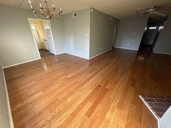 Spacious and inviting L-shaped family and dining room featuring elegant hardwood floors and a cozy wood-burning fireplace_perfect for relaxing or entertaining!