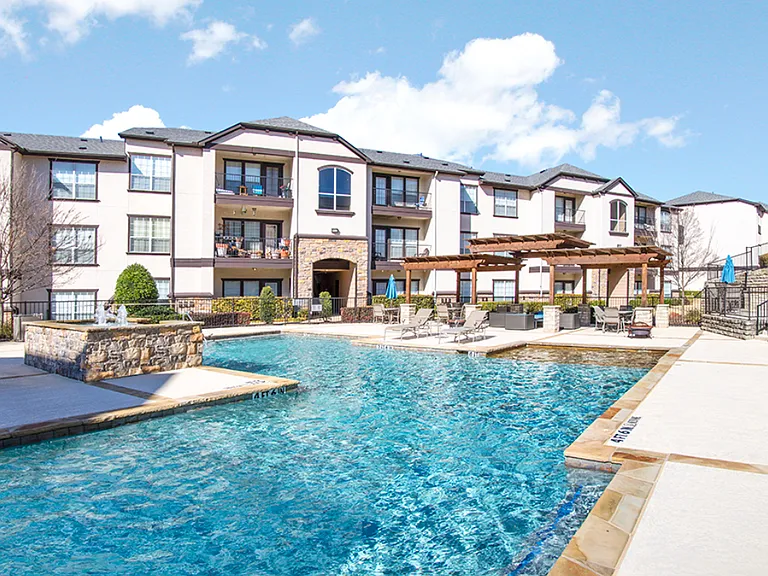 Sunlit swimming pool surrounded by modern apartment buildings and lounge seating