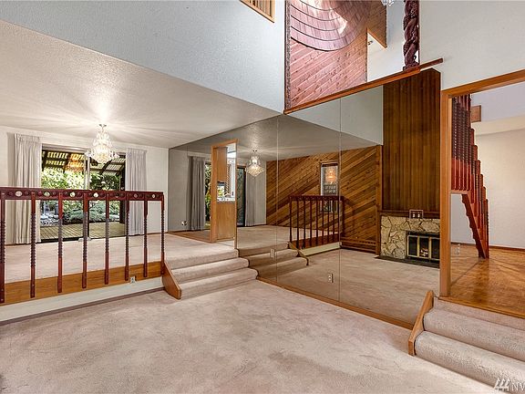 Formal living room with vaulted ceiling, gas fireplace and wood-lined wall above the staircase.
