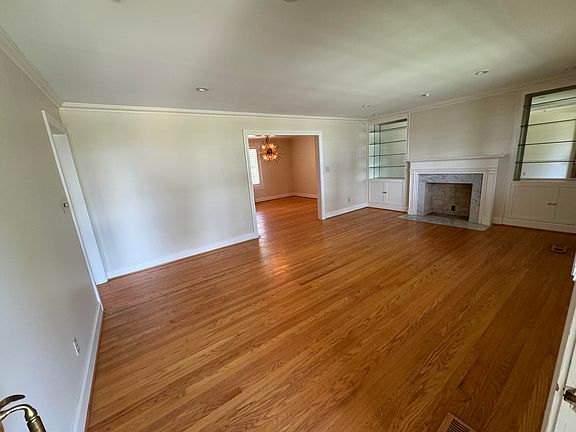 Living Room view from front door highlights mirror back / glass shelve book cases on either side of fireplace, from here you are just steps away from the dining room