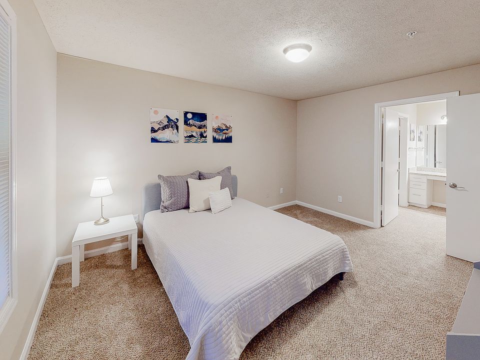 Gorgeous master suite equipped with a private bathroom, natural daylight, a queen bed, nightstand, vintage lamp and dresser.