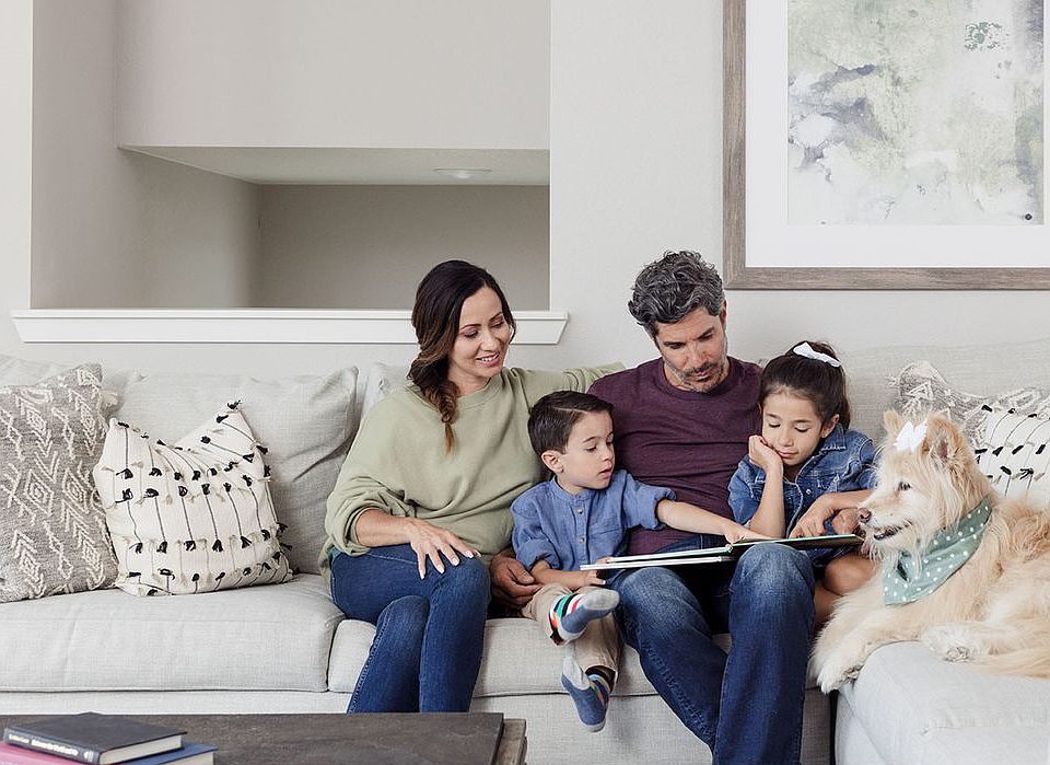 Image of a family on a couch representing a home in Oquirrh Mountain Ranch built by Oakwood Homes.