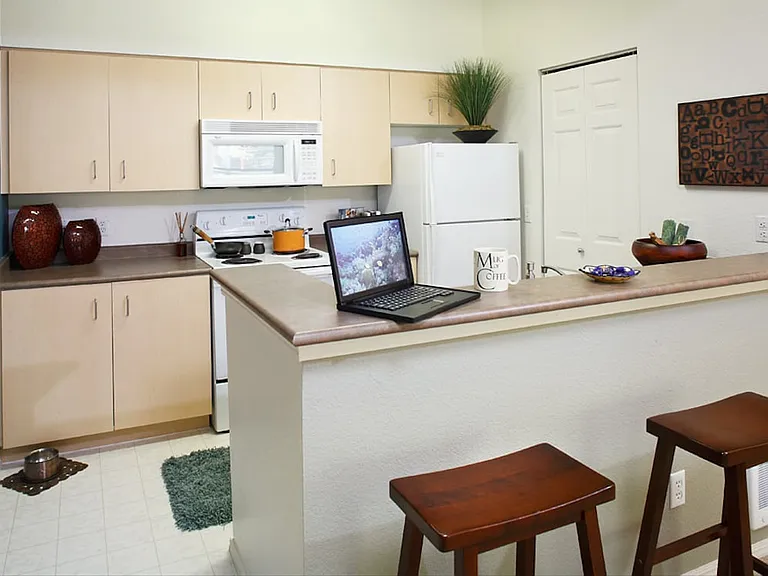 Classic Package I kitchen with white appliances, laminate countertops, maple cabinetry, and laminate flooring