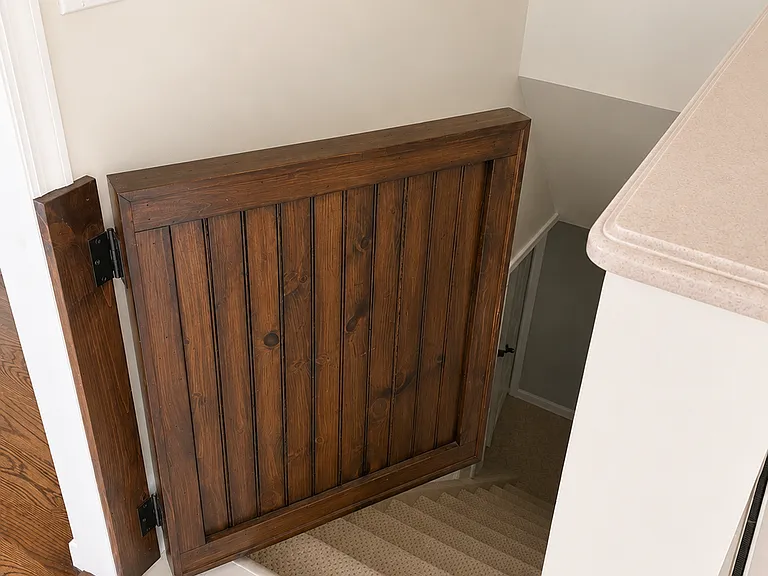stairway with custom wood gate to head down to the basement from the kitchen