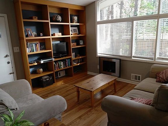 Light-filled living room shows vaulted ceilings, wall of windows and built-ins  Beautiful original oak hardwood floors