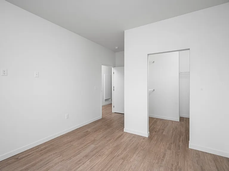 Bright and airy minimalist room with sleek wooden floors, white walls, and a spacious walk-in closet. Bright and airy minimalist room with sleek wooden floors, white walls, and a spacious walk-in closet.