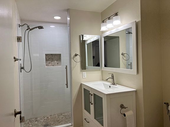 Downstairs bath with walk in shower and pebble tiled floor.