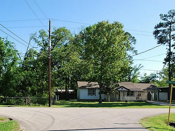 This street view shows the wooded lot, the home and the lot with a large garage/workshop