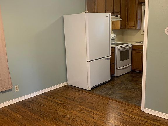 Living room with original wood floors and kitchen area.
