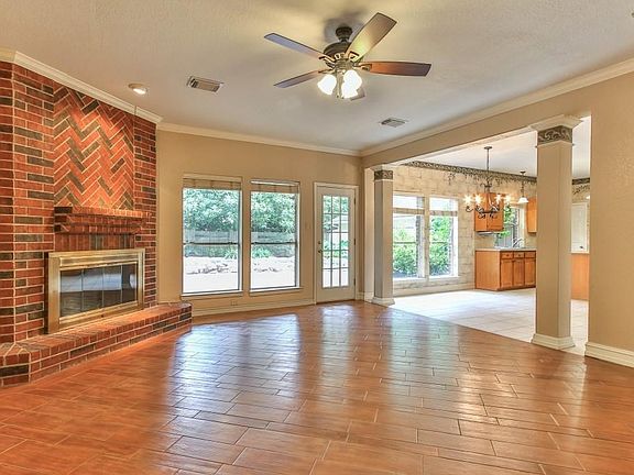Abundance of natural light in the den with inviting brick fireplace and large windows overlooking the swimming pool and covered patio.