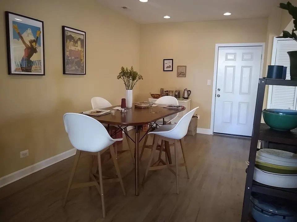 Dining room with the kitchen and laundry to the right, and a door leading to additional storage and driveway parking.