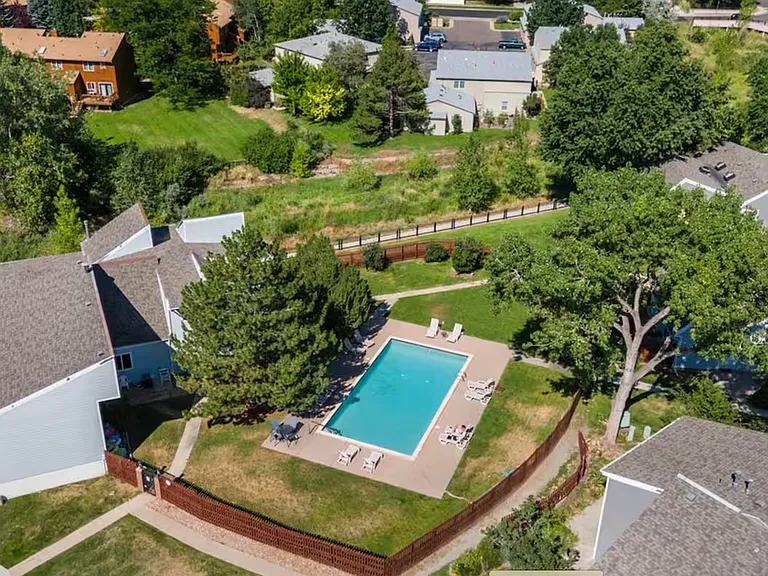 Aerial view of the peaceful neighborhood and pool_an inviting space to unwind with nature and sunshine all around.