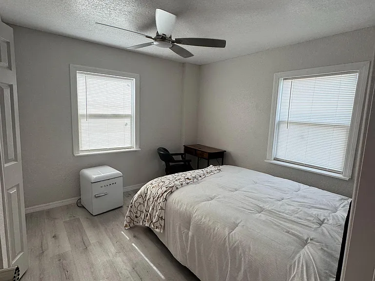 Private bedroom with two windows, ceiling fan, and easy-care flooring, plus space for a bed and compact work area.