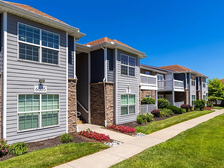 Elegant apartment exteriors with stone accents, spacious balconies, and well-manicured lawns, providing a picturesque and welcoming atmosphere.