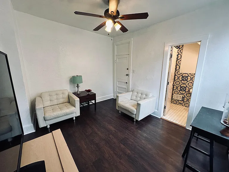 Living room view. Entry door on the left, bathroom door right. Laminate wood floors.
North facing window