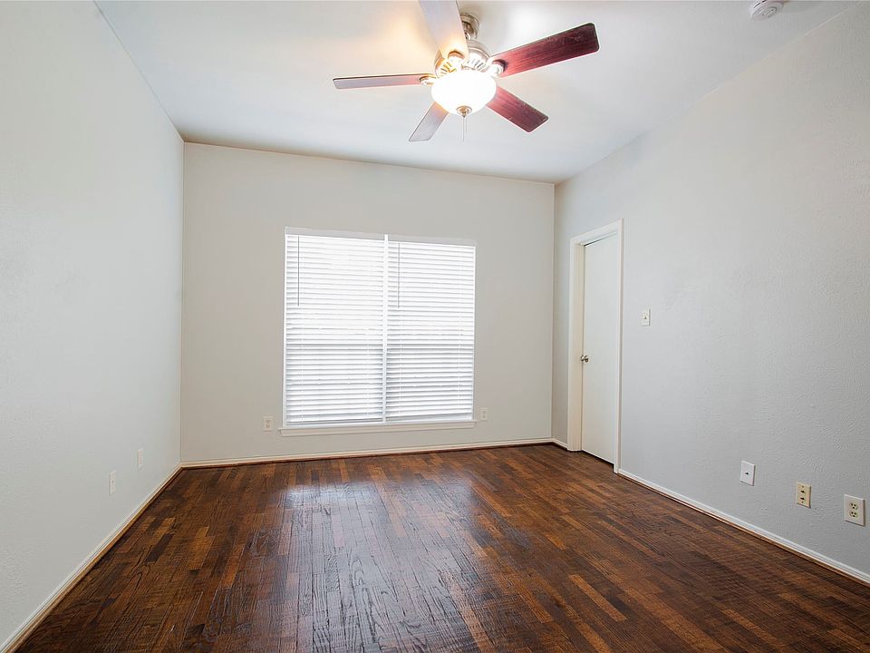 Room featuring wood-finish flooring, a vaulted ceiling, and a ceiling fan with light fixture
