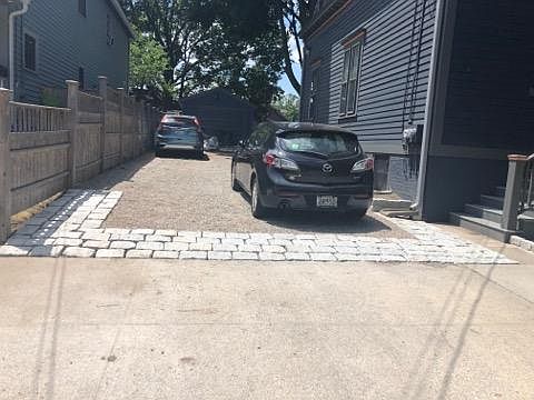 Driveway and studio garage with previous tenant parked at edge of driveway.