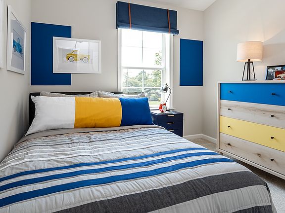 Carpeted secondary bedroom with large window in a DRB Homes York II model at the Townes at Tate Mano