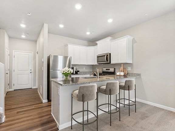 The kitchen has stainless steel appliances and plank flooring.