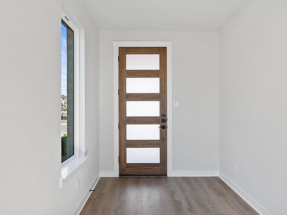 A simple, minimalist interior with a wooden door and a window, set against a plain white wall and ha