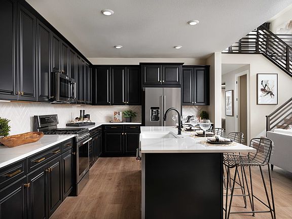 A modern and sleek kitchen with dark cabinets, white countertops, and stainless steel appliances, co