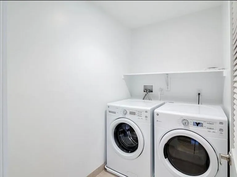 Hallway between bedrooms has dedicated laundry room with front-loading washer and dryer