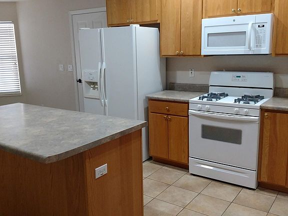 Kitchen island is great space for food preparation. House includes all kitchen appliances - refrigerator, gas stove, over the range microwave, and dishwasher