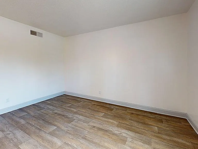 Inviting modern room with elegant hardwood flooring, featuring neutral walls and ample natural light.
