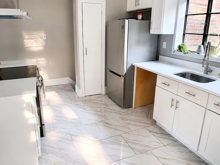 Updated kitchen with white shaker cabinets, quartz-style counters, stainless appliances, and a large window over the sink.