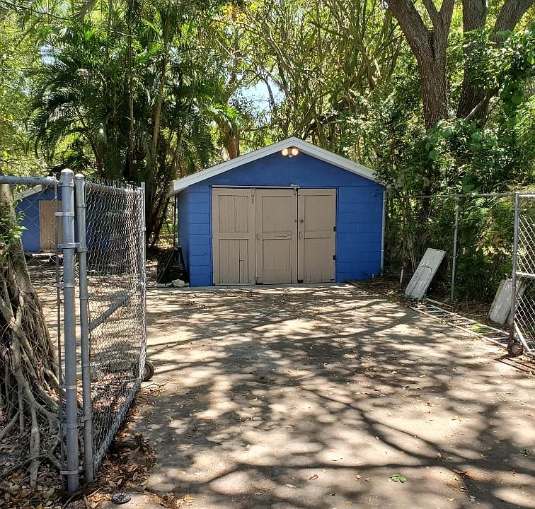 Stand alone garage/workshop at end of driveway can be secured behind the chain link fence gates.