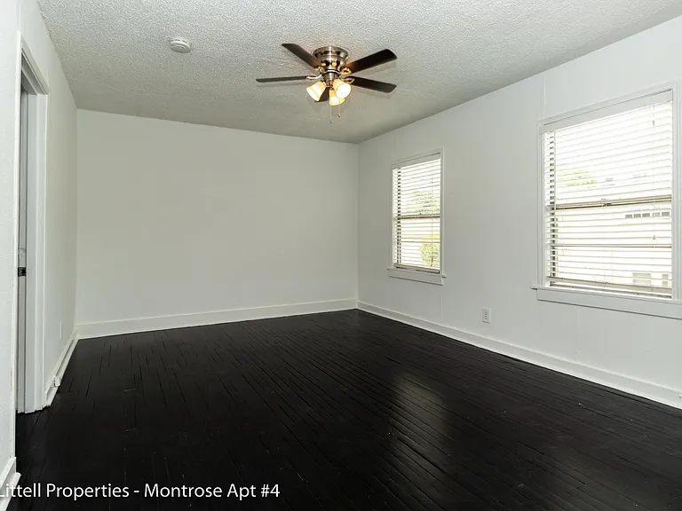 Living area with dark floors, ceiling fan, and 2 windows