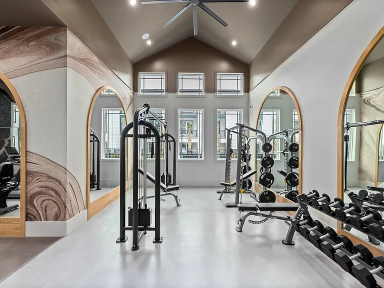 Modern apartment fitness studio with strength training equipment, free weights, and elevated wellness amenities.
