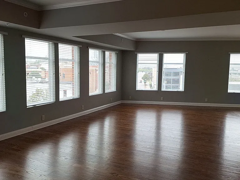 The Penthouse living area is spacious and has luxurious window lighting and hardwood floors.