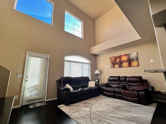 Living room with high ceiling and remote operated blinds.
