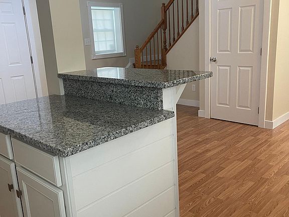 Kitchen Island with Bar, Storage Closet Door Seen in Background near Stairs.