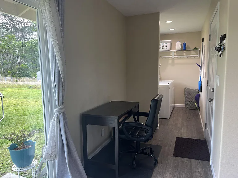 Office desk and chair in nook leading to 2 car garage and laundry