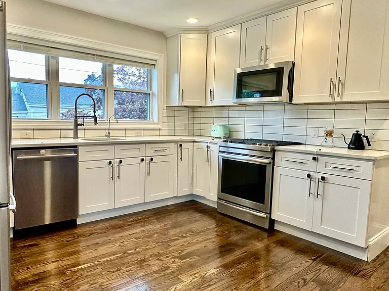 Updated kitchen with high-end JennAir appliances, gas stove, venting system, white cabinetry, and generous storage.
