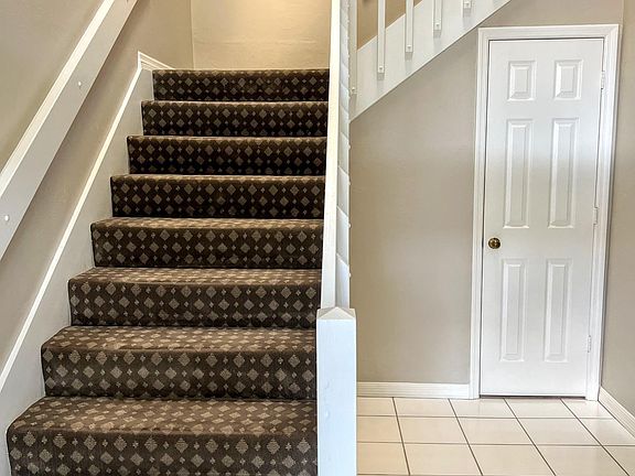Foyer and stairs to main living space that includes vaulted ceilings and golf/lake views. Mini storage closet under stairway.